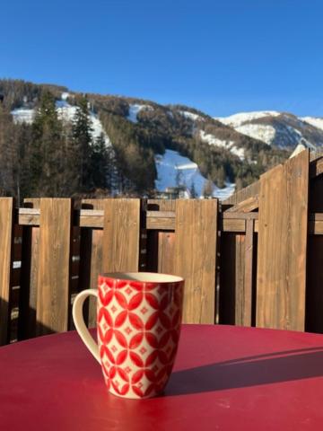 une tasse de café rouge assise sur une table rouge dans l'établissement Studio grande terrasse Pra loup 1600, à Uvernet