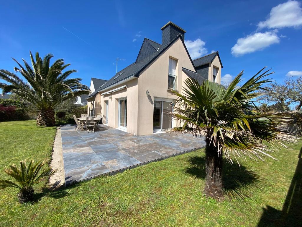 une maison avec une terrasse et des palmiers dans la cour dans l'établissement Maison 5 pièces 6 a 7 personnes à proximité de la plage du Fort-Bloqué - Wi-fi - Maeline, à Ploemeur