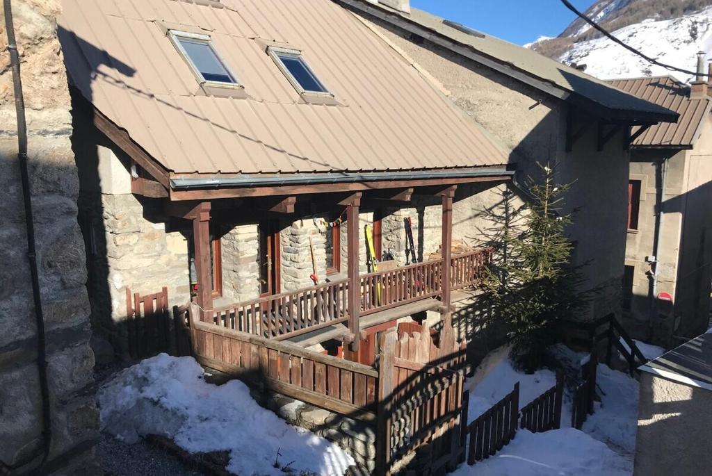 a house with a wooden porch with a fence at Chalet les Aurores au coeur du village La Grave - La Meije in La Grave