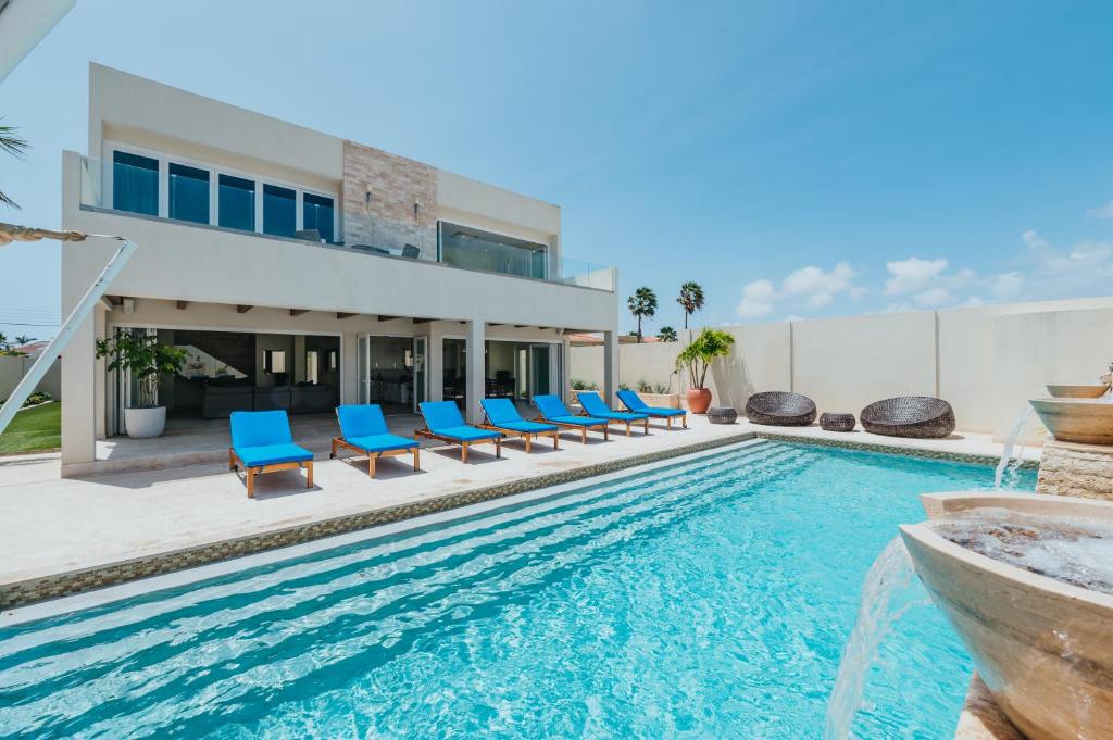 a swimming pool with blue chairs and a house at LUX 2BR Pool 5mins Beach Villa Ocean by Bocobay in Palm-Eagle Beach