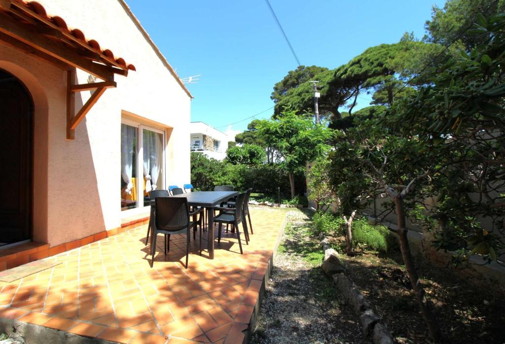 un patio avec une table et des chaises dans une cour dans l'établissement HYEGRASSE Villa pour 6 personnes à 100 mètres de la plage situé sur le Port d'Hyères, à Hyères