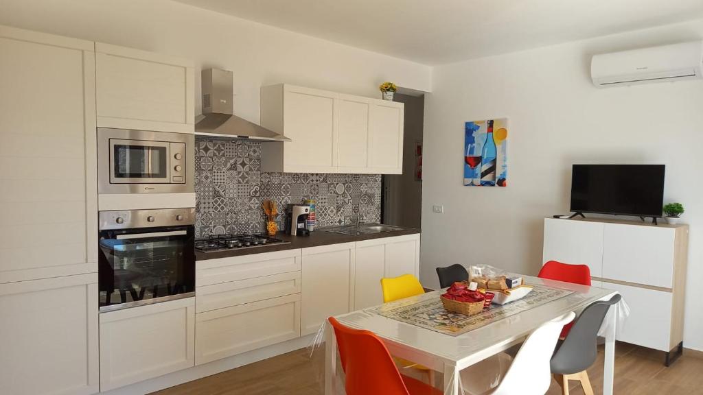 a kitchen with white cabinets and a table with chairs at Villa Saint George in Scopello