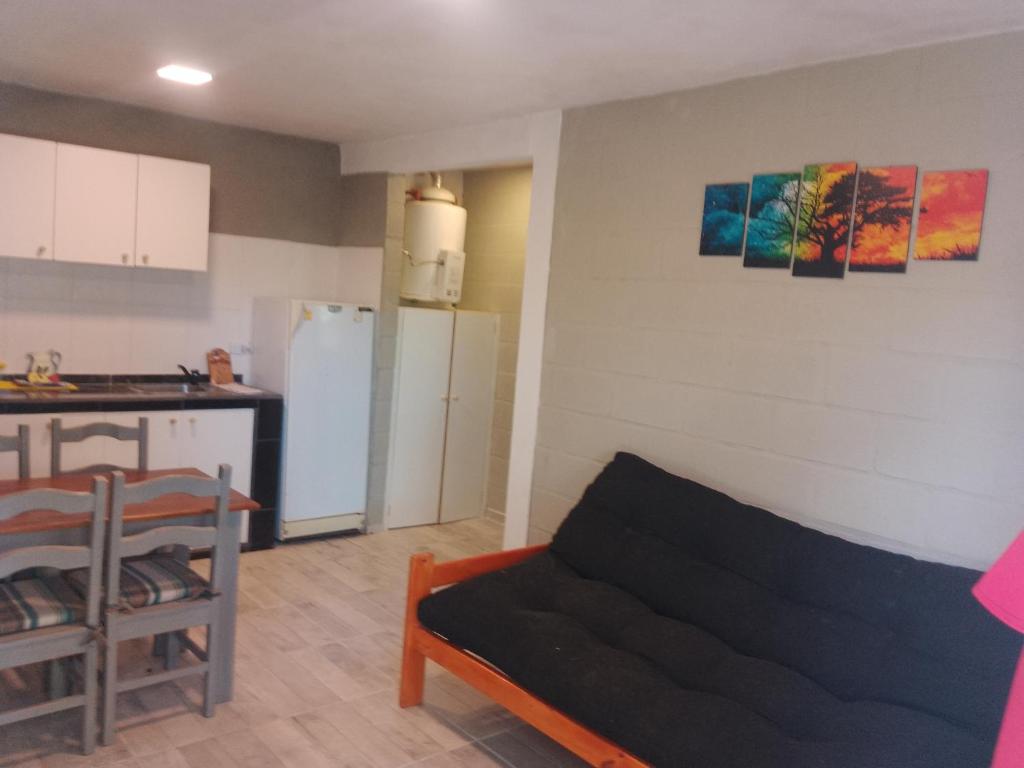 Una sala de estar con un sofá y una cocina. en Cabaña Calamuchita Rumipal, en Villa Rumipal