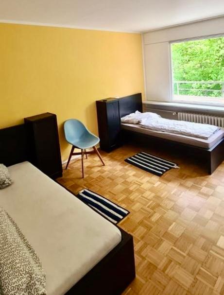 a room with two beds and a chair and a window at GMA Apartment B16 in Lahr