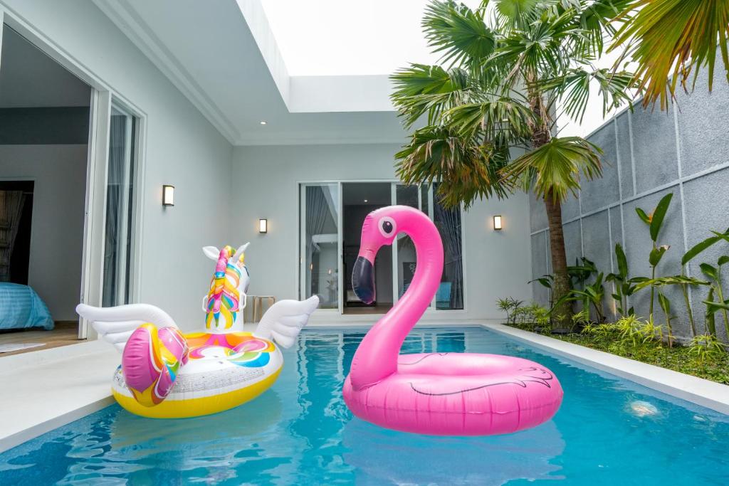 a swimming pool with two inflatable flamingos in a house at Luxor Villa Private Pool in Ngaglik