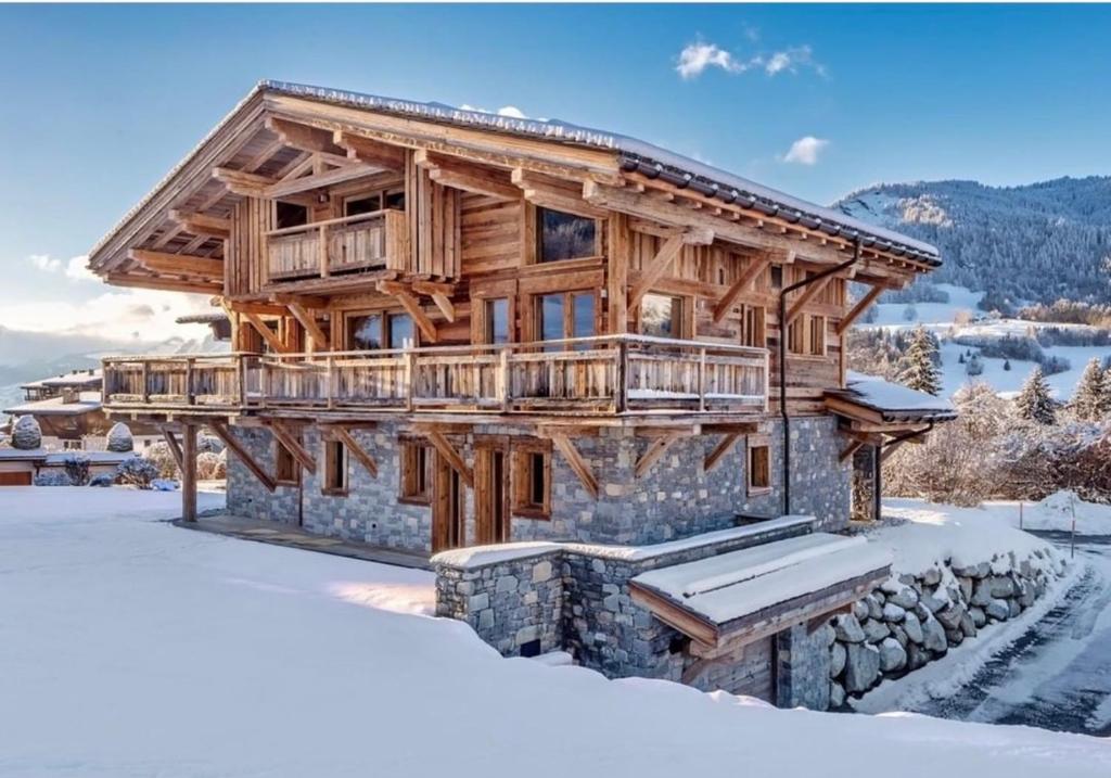 a log cabin in the snow with a stone wall at Chalet des rêves in Megève