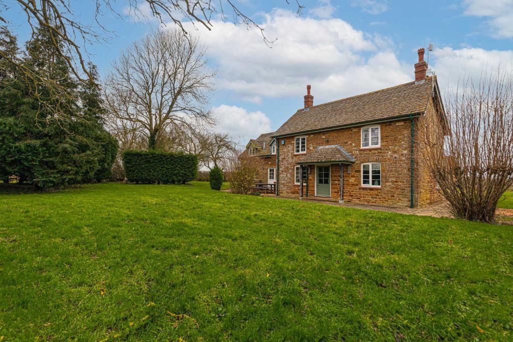 a large brick house with a grassy yard at Great Easton Lodge in Great Easton