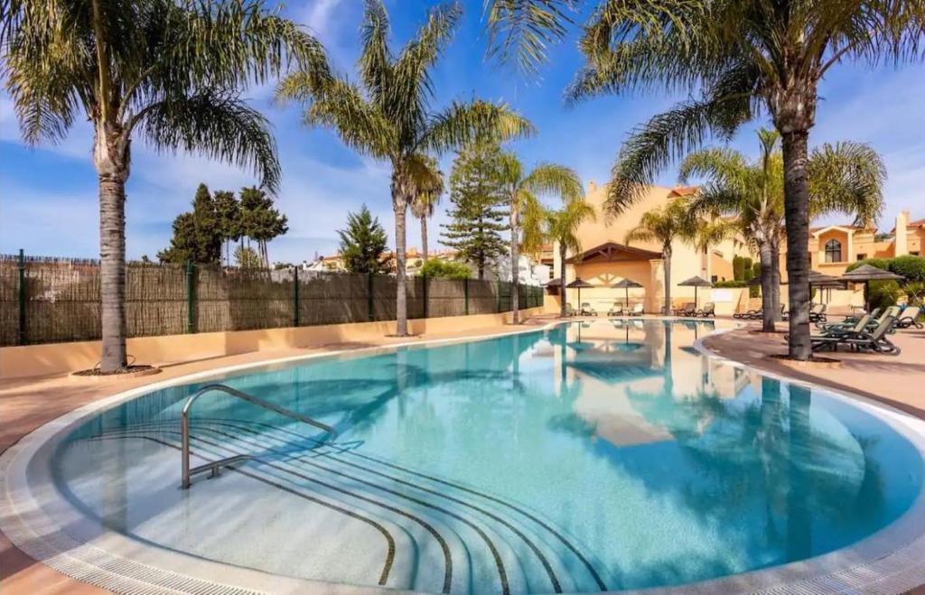 una piscina con palme e recinzione di Praia da Luz - Resort a Luz