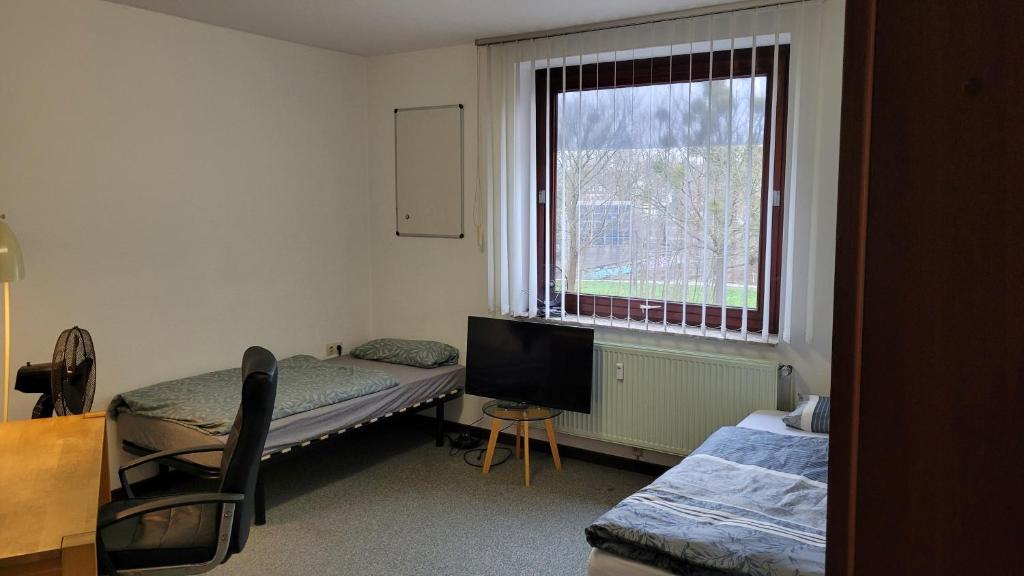 a room with two beds and a tv and a window at City- und Messeapartment Hildesheim in Hildesheim