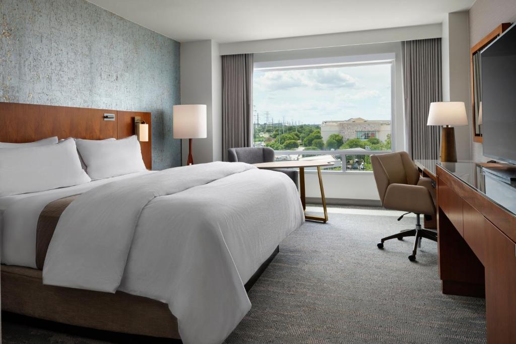 a hotel room with a bed and a desk and a window at The Westin Austin at The Domain in Austin