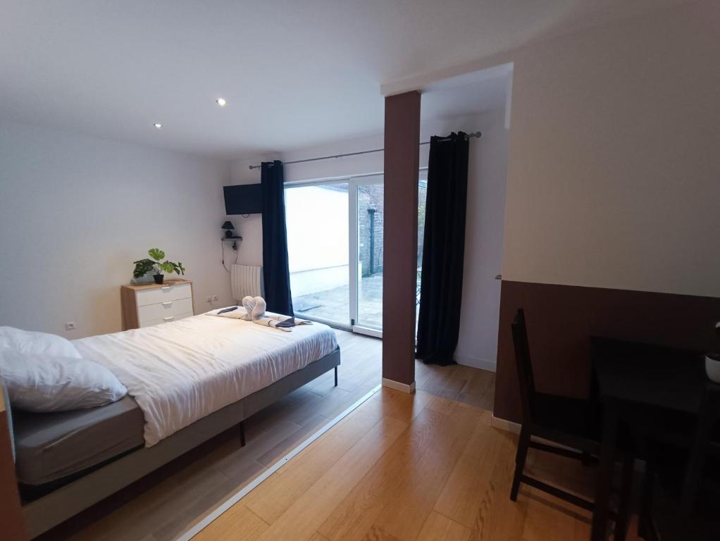 une chambre avec un lit et une porte coulissante en verre dans l'établissement Hello Sunshine - Studio avec terrasse Malo Plage, à Dunkerque