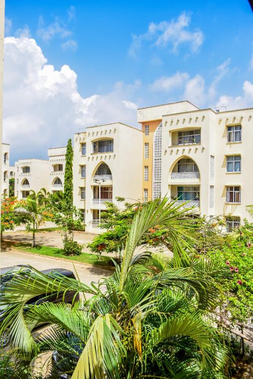 an apartment building with palm trees in the foreground at Mi Casa Su Casa in Mtwapa