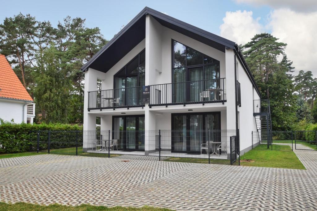 a white house with a black roof at Być Morze in Pobierowo