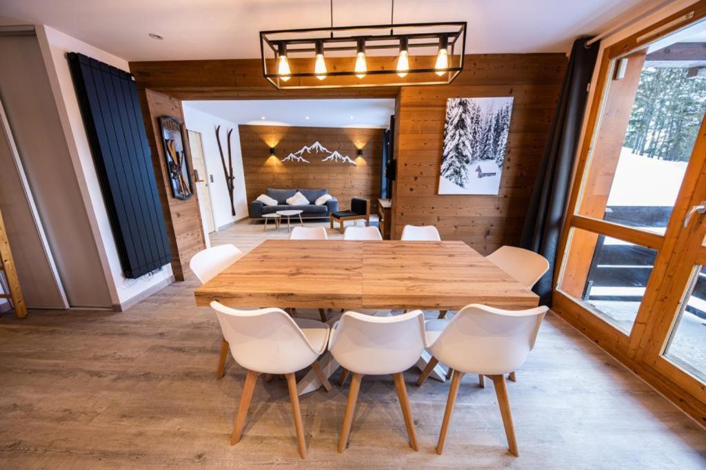 a dining room with a wooden table and white chairs at Superbe vue, accès skis aux pieds, très agréable in Courchevel