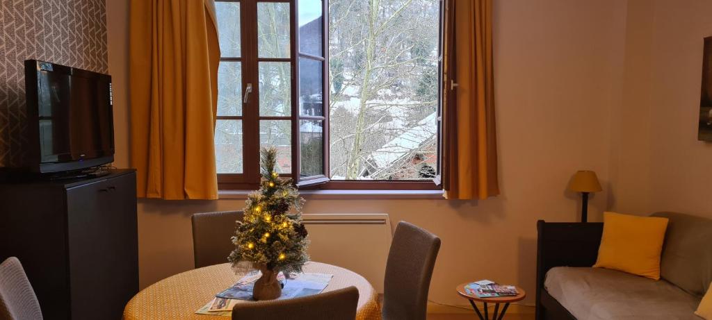- un salon avec une table et un arbre de Noël dans l'établissement Le Porteur de Glace Classé 2 étoiles, à Aulus-les-Bains