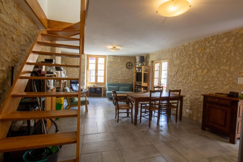 a living room with a wooden staircase and a table and chairs at La maison de famille in Mussidan