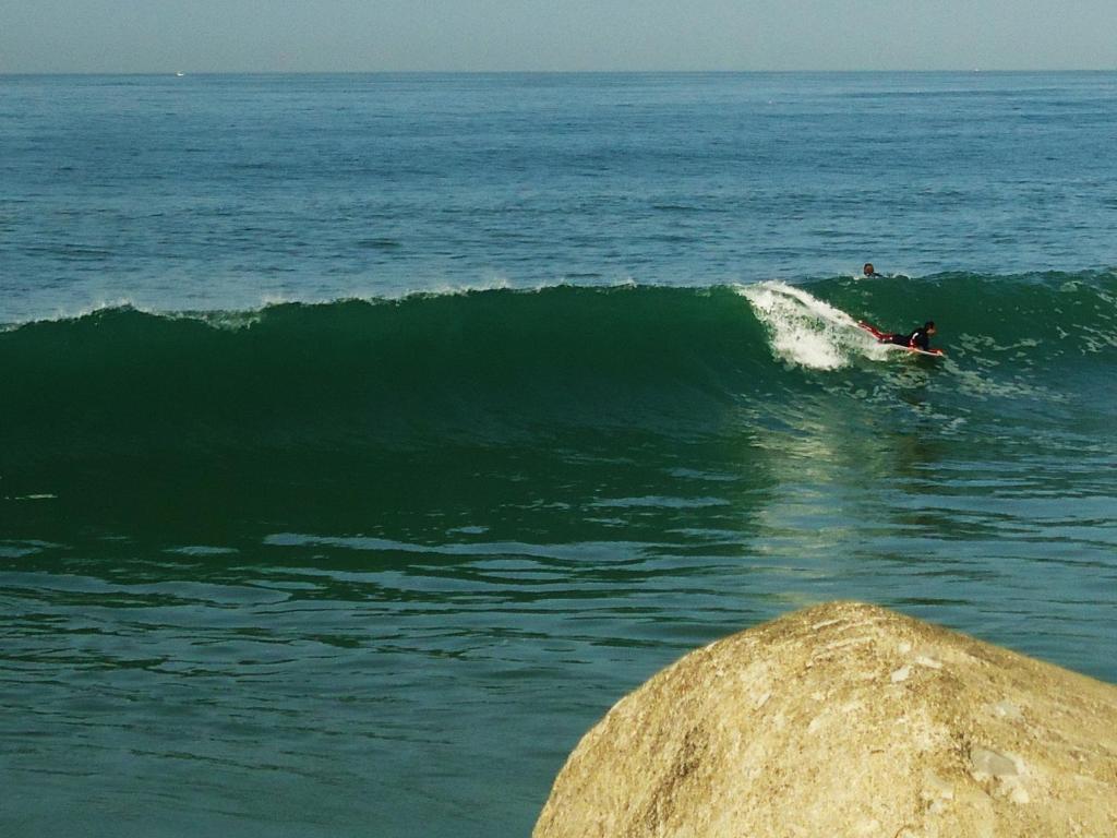 una persona montando una ola en una tabla de surf en el océano en Galante Beach Apartment, en Figueira da Foz