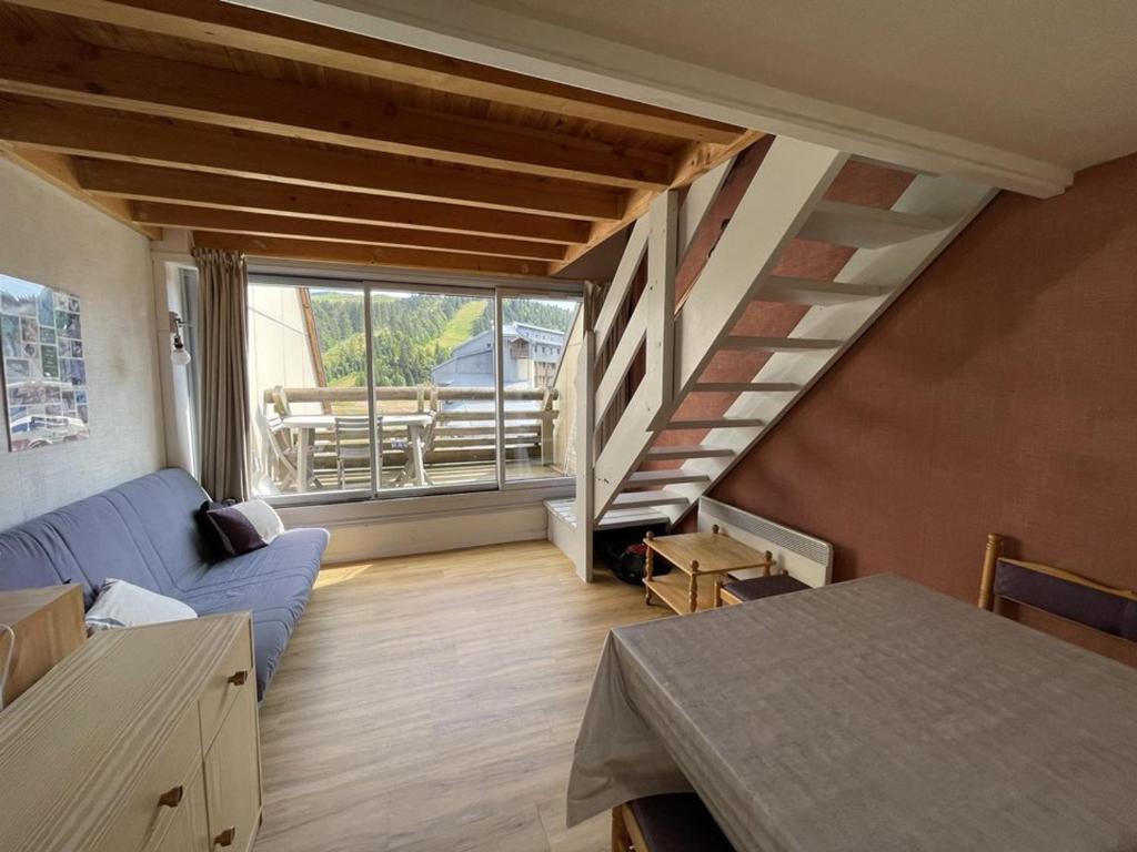 - un salon avec un canapé bleu et un escalier dans l'établissement Duplex cosy 6-8 pers. pieds des pistes avec balcon - FR-1-787-88, à Laveissière