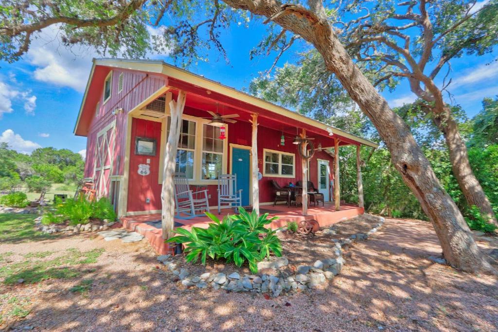 una casa roja con un árbol delante en Sunflower Ridge Cabin, en San Marcos