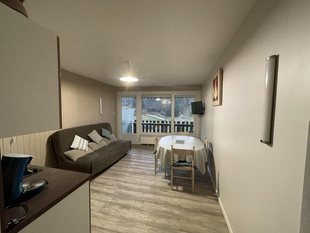 ein Wohnzimmer mit Sofa und Tisch in der Unterkunft Studio rénové avec balcon, au pied des pistes, accès WIFI - FR-1-787-53 in Laveissière