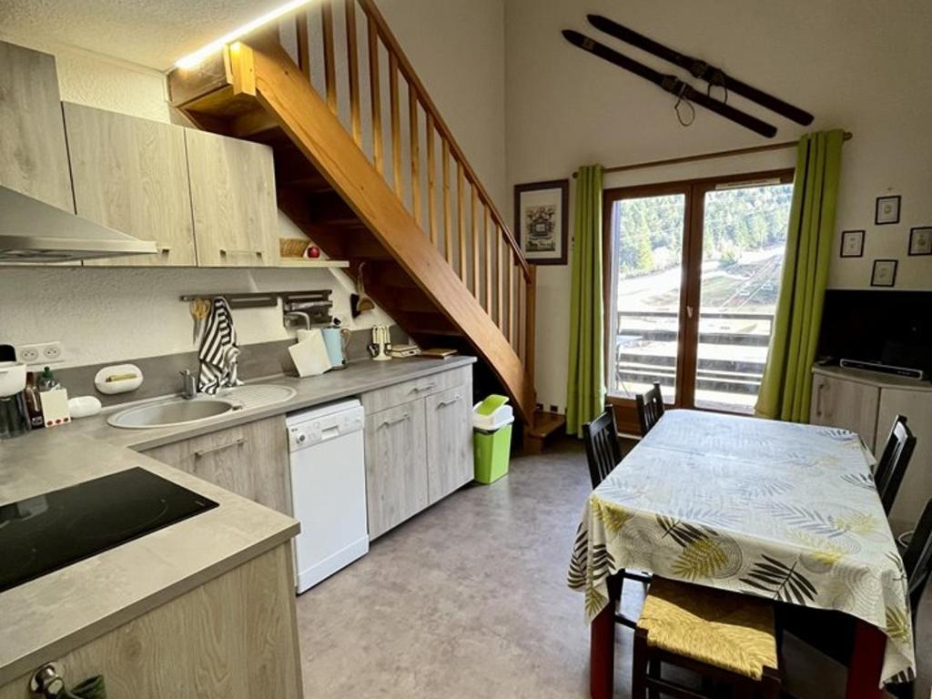 une cuisine avec une table et un évier, ainsi qu'un escalier. dans l'établissement Duplex T3 balcon au cœur du Lioran, proche pistes - FR-1-787-89, à Laveissière