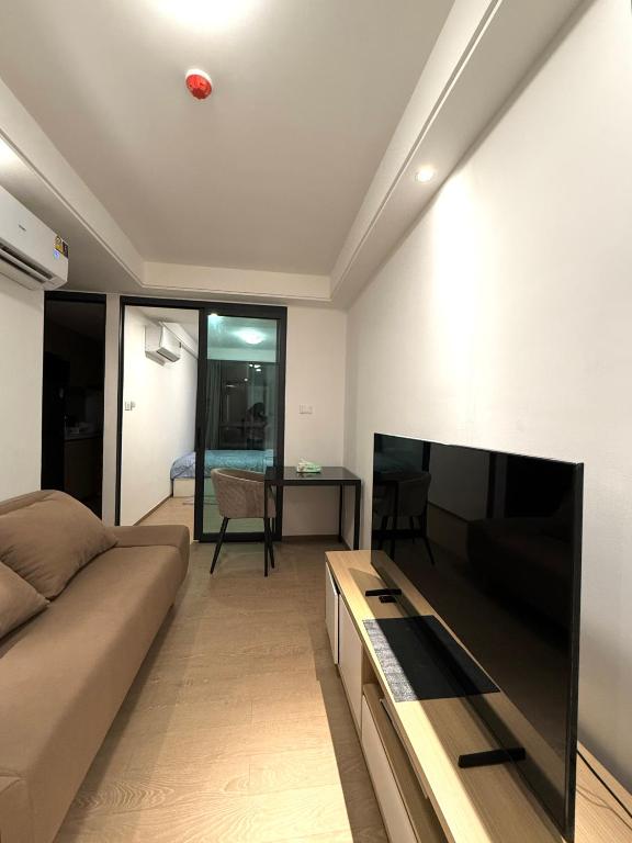 a living room with a couch and a flat screen tv at Regal 40 Srinakarin Apartment in Bangkok