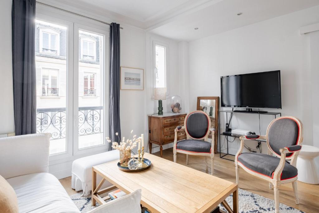un salon avec une télévision et deux chaises et une table dans l'établissement Veeve - Cotton White, à Paris