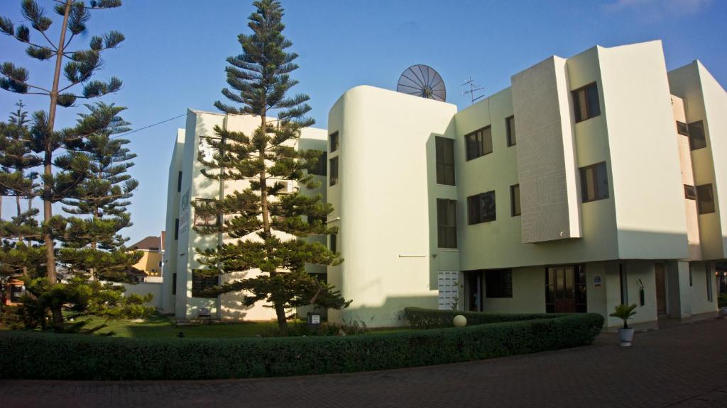 a white building with trees in front of it at Pekan Hotel in Accra