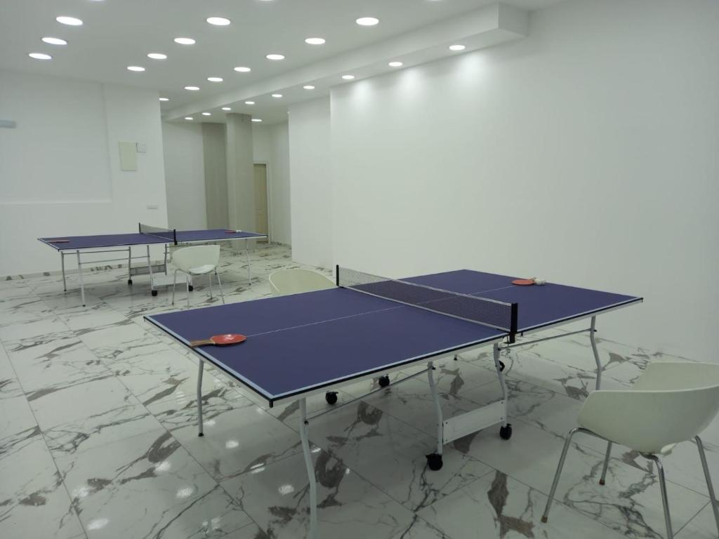 two ping pong tables in a room with chairs at Apartments Bramar in Zlatibor