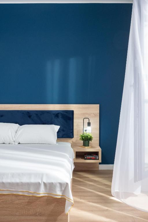 a blue bedroom with a white bed and a blue wall at ELIZA Apartments - powered by NEO - private parking in Timişoara