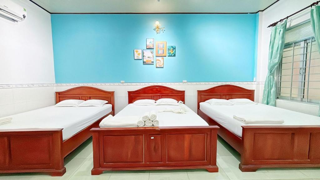 two beds in a room with a blue wall at Quoc Dinh Guest House in Mui Ne