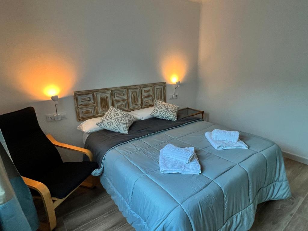 a bedroom with a blue bed and a chair at Casas de Valtravieso El Jardín in El Pozo de los Frailes