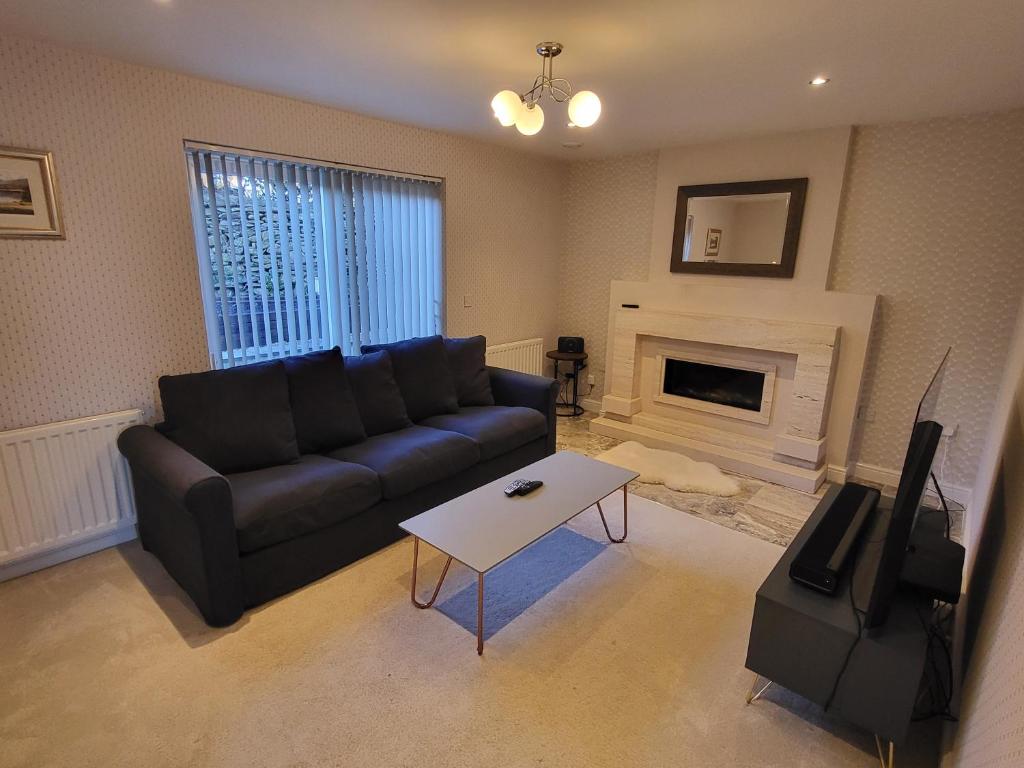 a living room with a black couch and a fireplace at Anchor Gardens Villa in Lindal in Furness