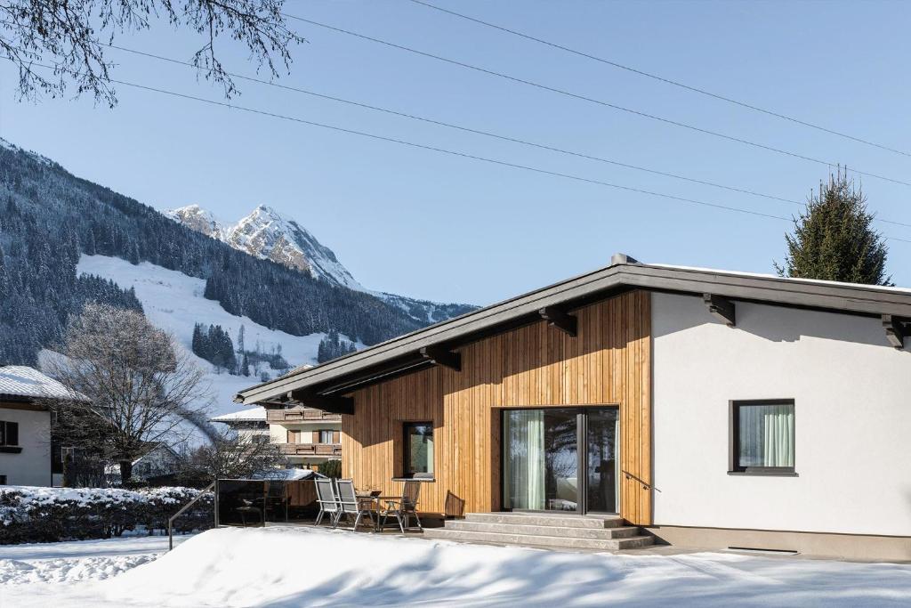 a house in the snow with mountains in the background at Dorfchalet by we rent in Dorfgastein