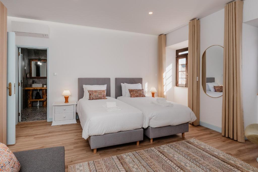 une chambre avec un grand lit avec des draps blancs dans l'établissement Casa da Cerca, à Runa