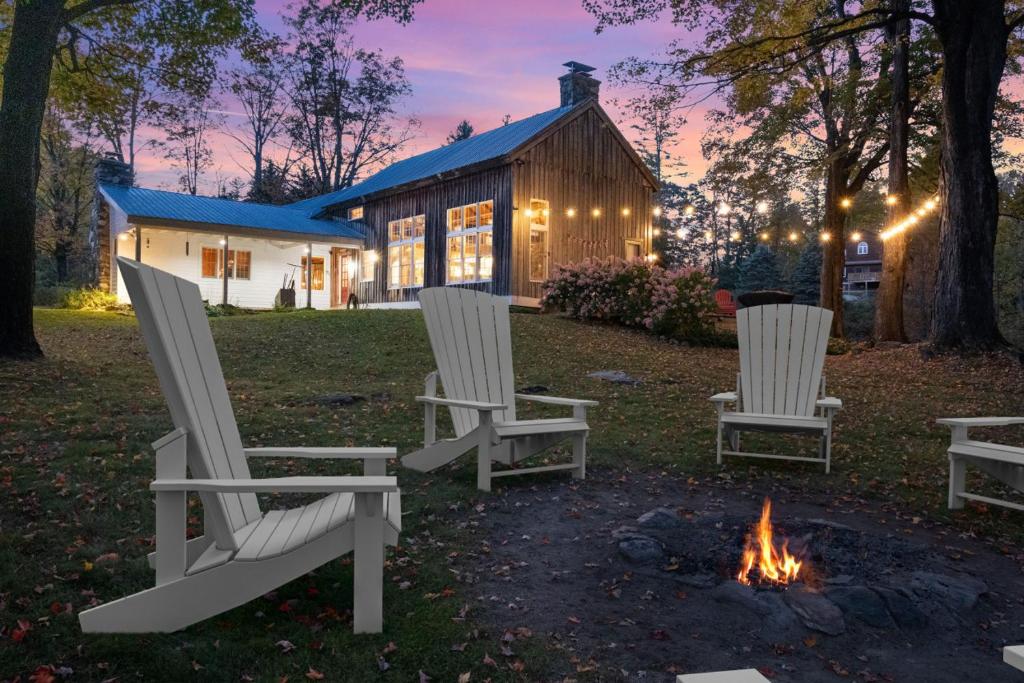 three chairs sitting around a fire in front of a house at Modern Lux Cabin w Mtn Views and Fire Pit in Stratton