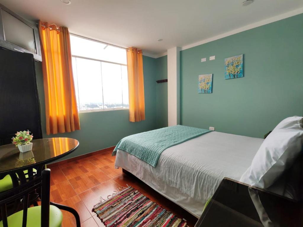 a bedroom with a bed and a table and a window at Catag Wasi Casa hospedaje in Cajamarca
