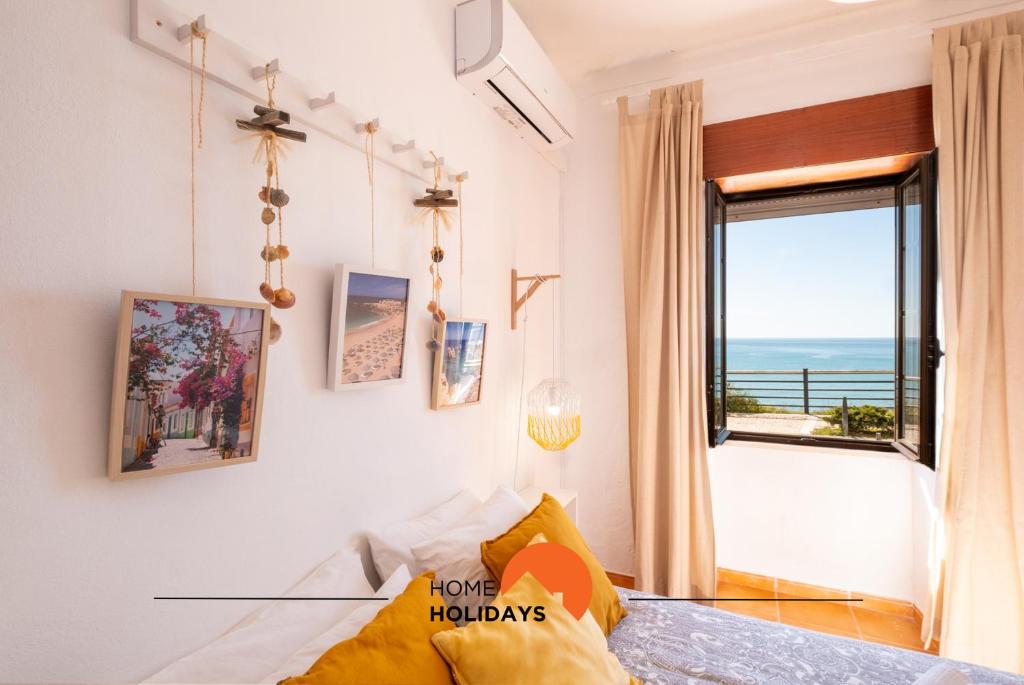 #003 Cottage By Home Holidays في Caliços: غرفة بسرير ونافذة مطلة على المحيط