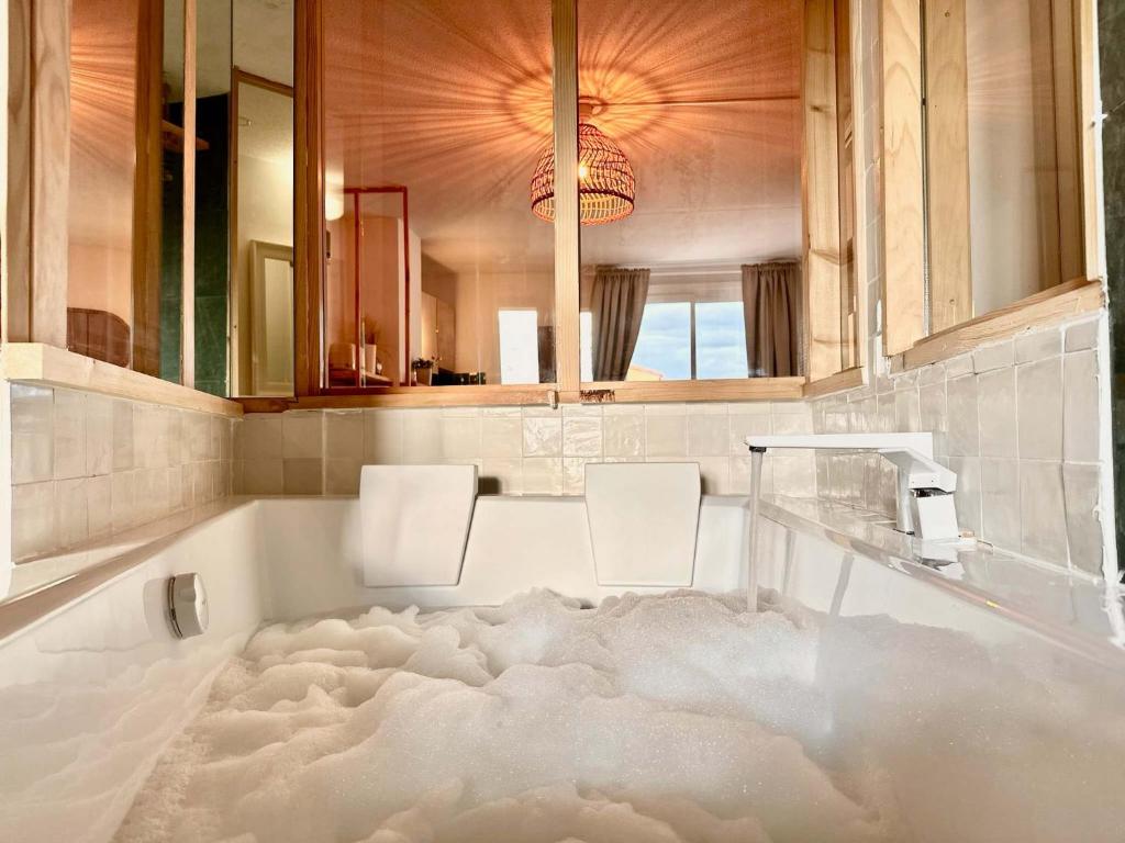 La salle de bains est pourvue d'une baignoire recouverte de neige. dans l'établissement Loft Style Architecte - Bain Duo et Cinema - Cap d'Agde, au Cap d'Agde