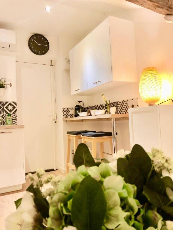 une cuisine avec des placards blancs et une horloge murale dans l'établissement Joli nid douillet au Vieux-Port, à Marseille
