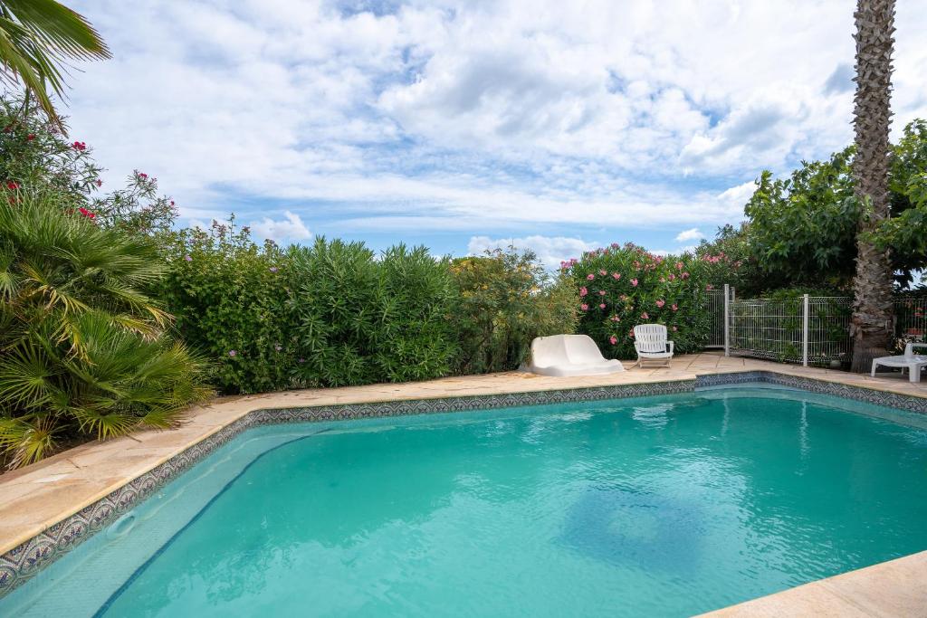 een zwembad met een stoel in de tuin bij Villa Avec Piscine partagée in Cap d'Agde