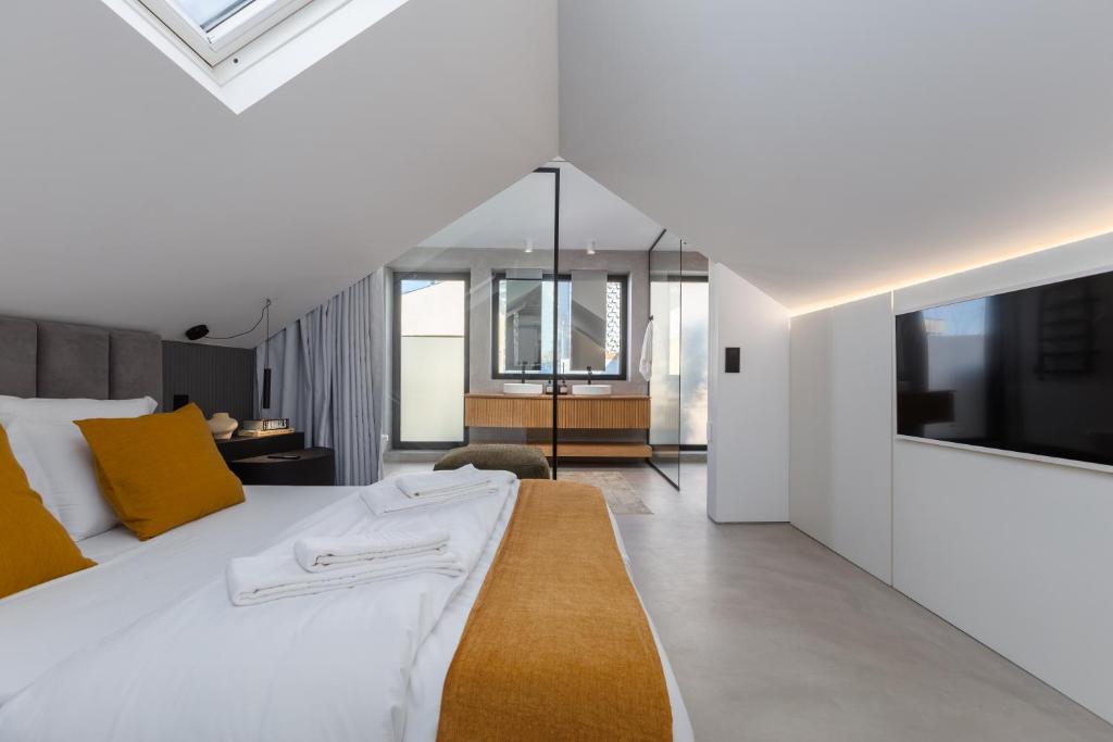 a bedroom with a large white bed and a television at Santiago Beach House in Leça da Palmeira