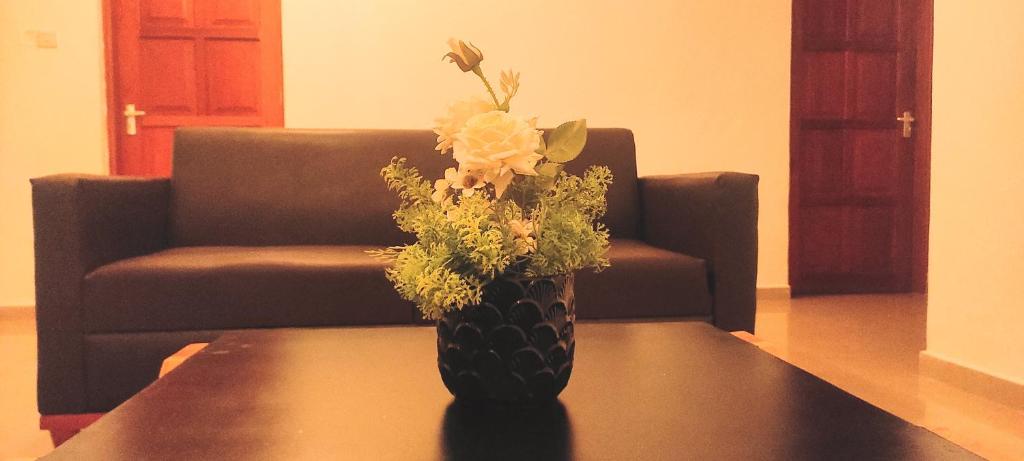 a vase with flowers sitting on a table in front of a couch at La Casa De Papel Morogoro Apartment by Monalisa in Morogoro