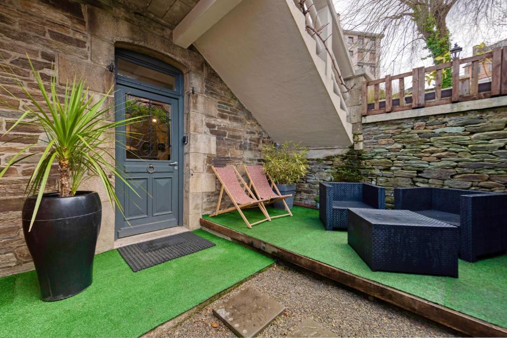 une terrasse couverte avec une porte bleue, des chaises et une plante dans l'établissement Le cocooning, à Lannion