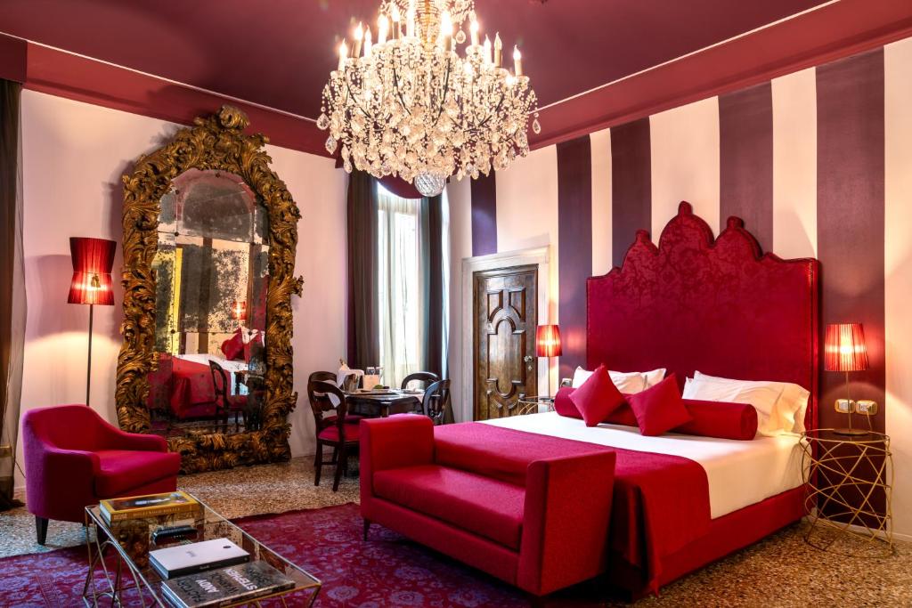 a bedroom with a large red bed and a chandelier at Excess Venice Boutique Hotel & Private Spa - Adults Only in Venice