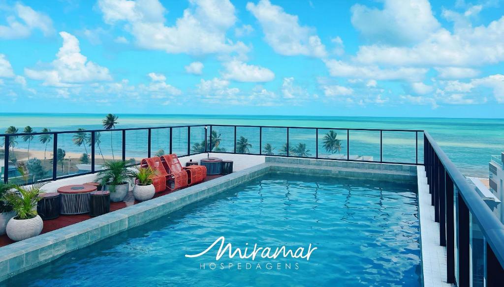 a swimming pool with the ocean in the background at Get By Side 50 Metros da Praia - Jardim Oceania in João Pessoa