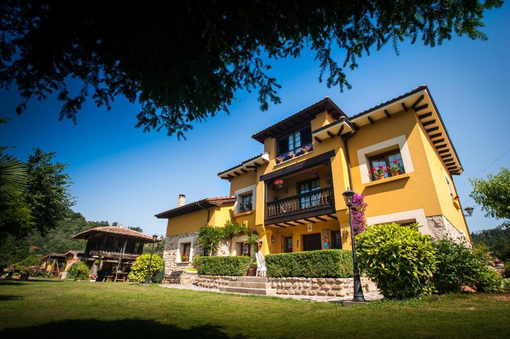 ein gelbes Haus mit Balkon und Hof in der Unterkunft Casa de Aldea Riosol in Cangas de Onís