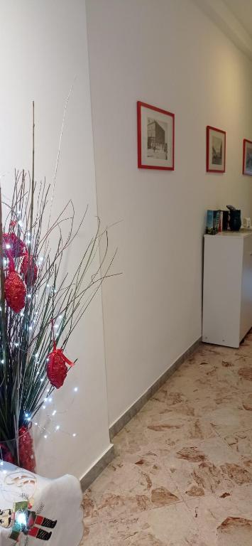 a white wall with a vase with red balls in it at CasaRA in Bari
