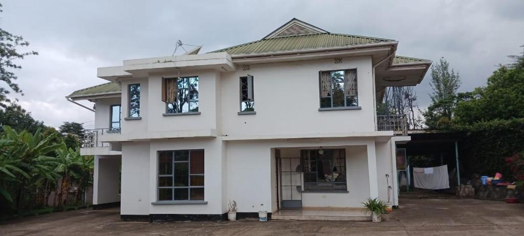 ein weißes Haus mit Fenstern und einem Dach in der Unterkunft Mara Home 2 in Arusha