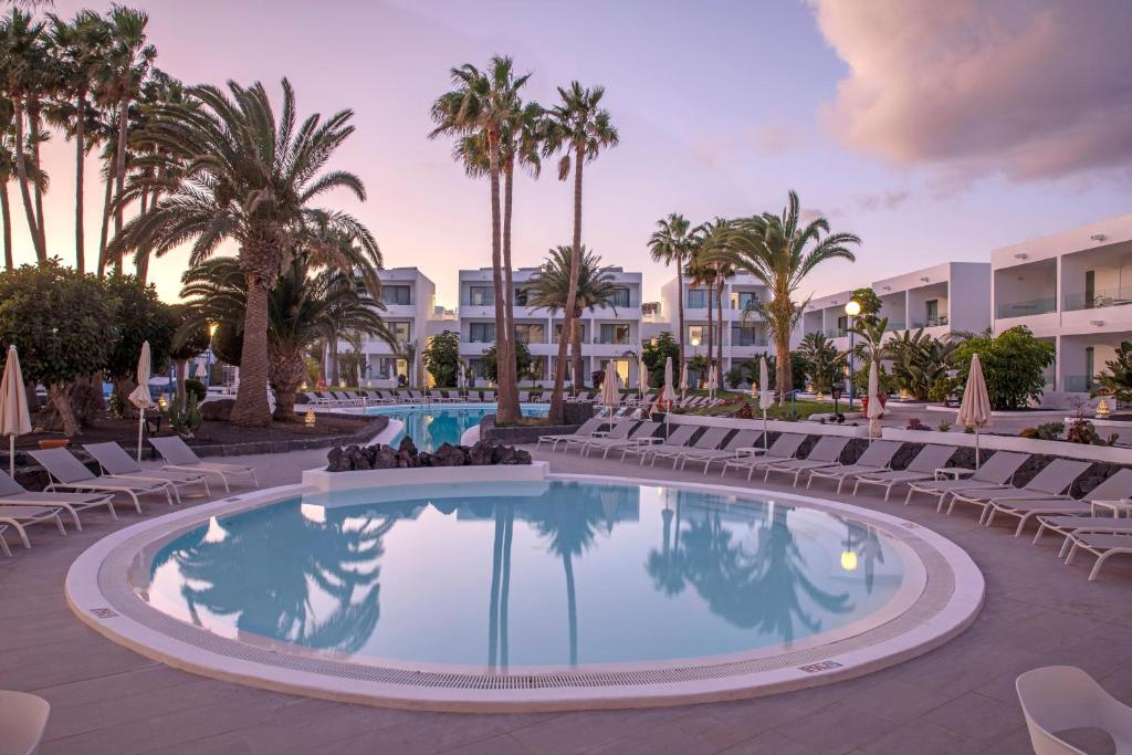a pool at the resort with chairs and palm trees at Oasis Lanz Beach Mate in Costa Teguise